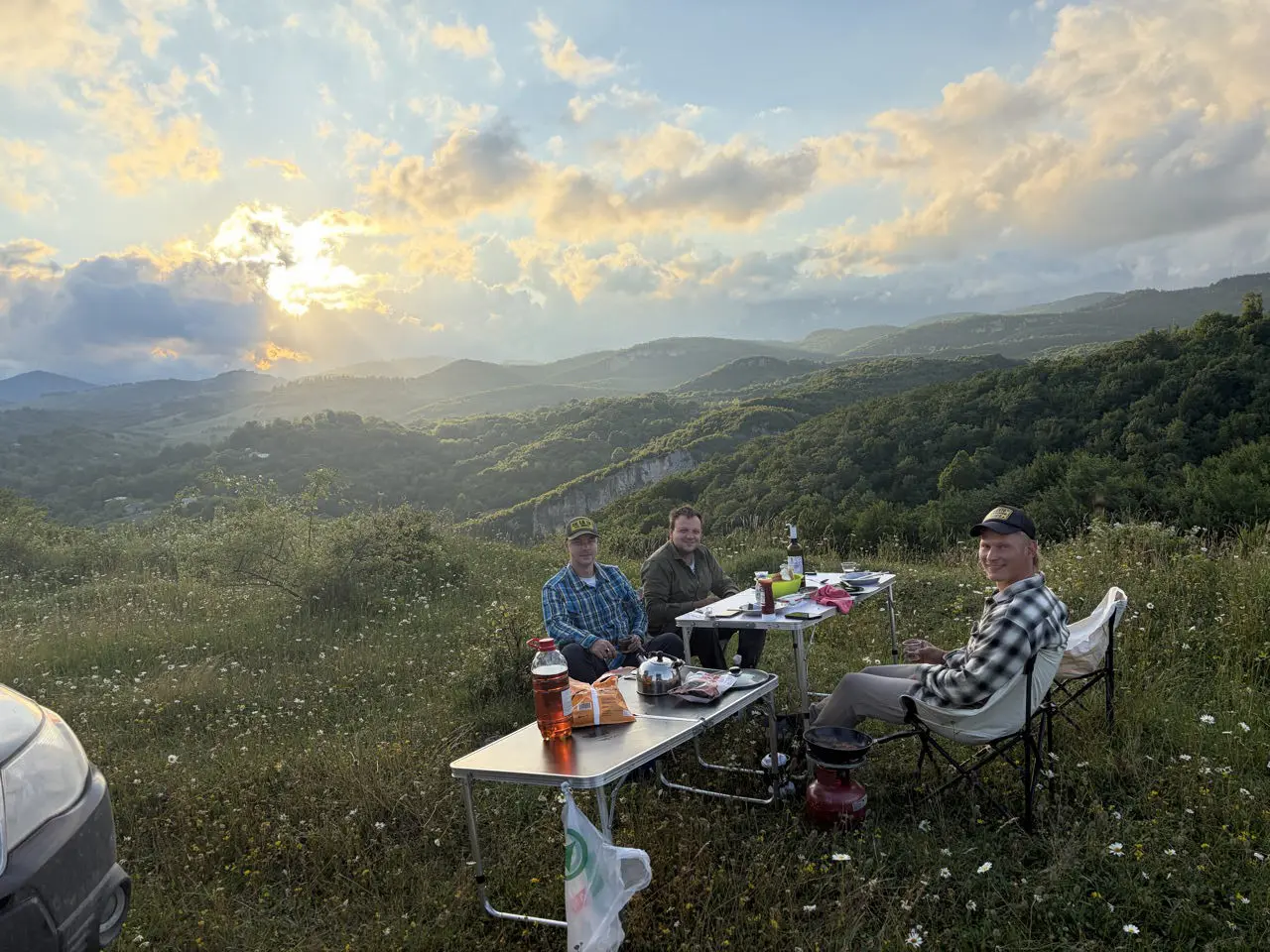 drie mannen die bij zonsondergang kamperen in de bergen van Georgië