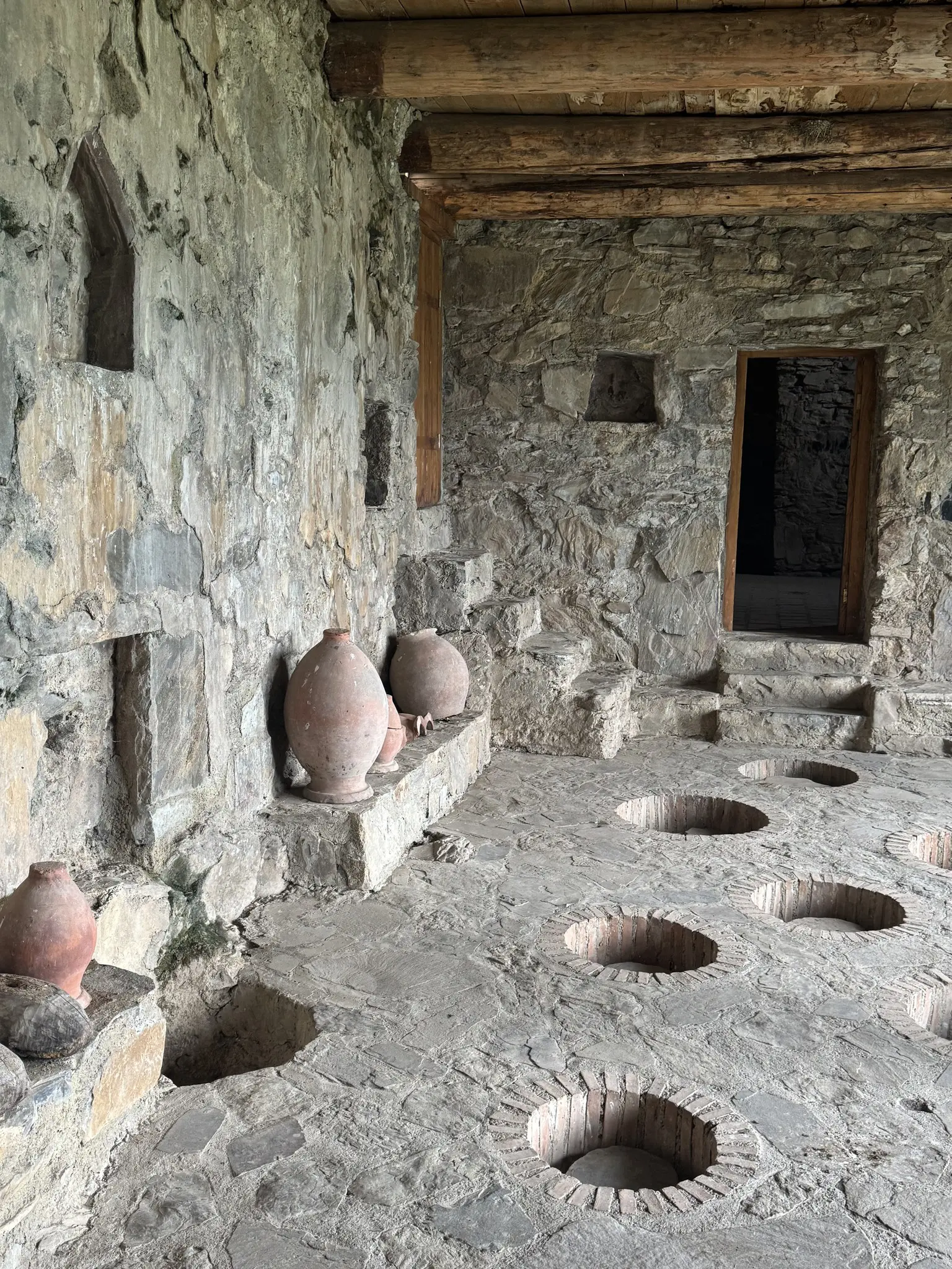 ancient stone room with clay amphorae and floor pits in Georgia
