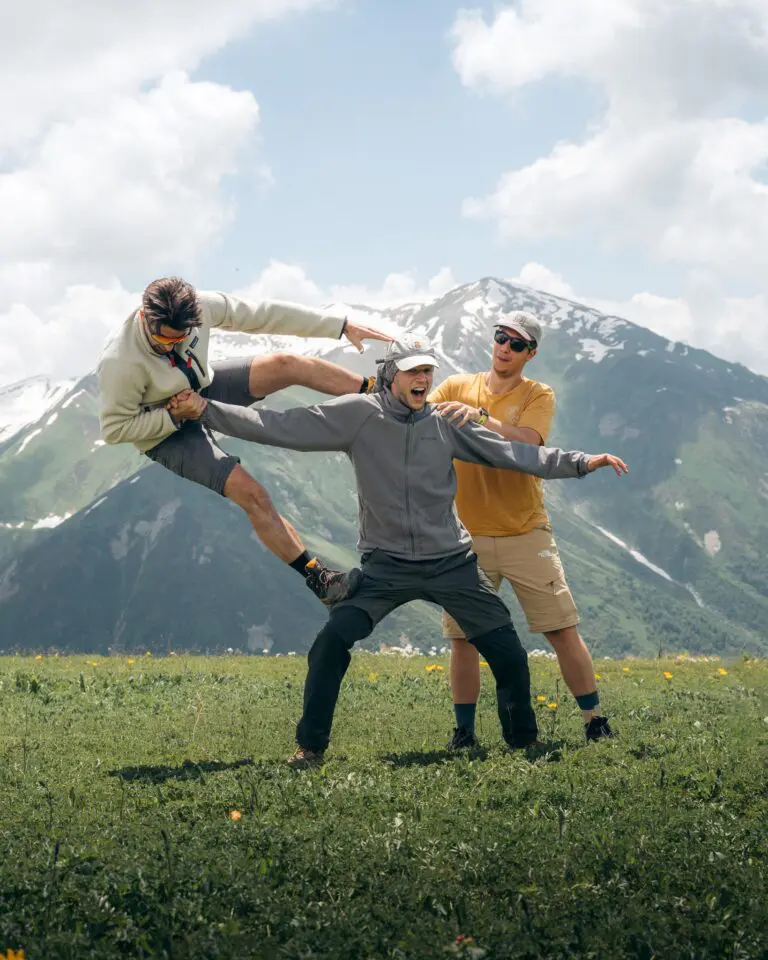 three friends balancing in a funny pose in a mountain meadow